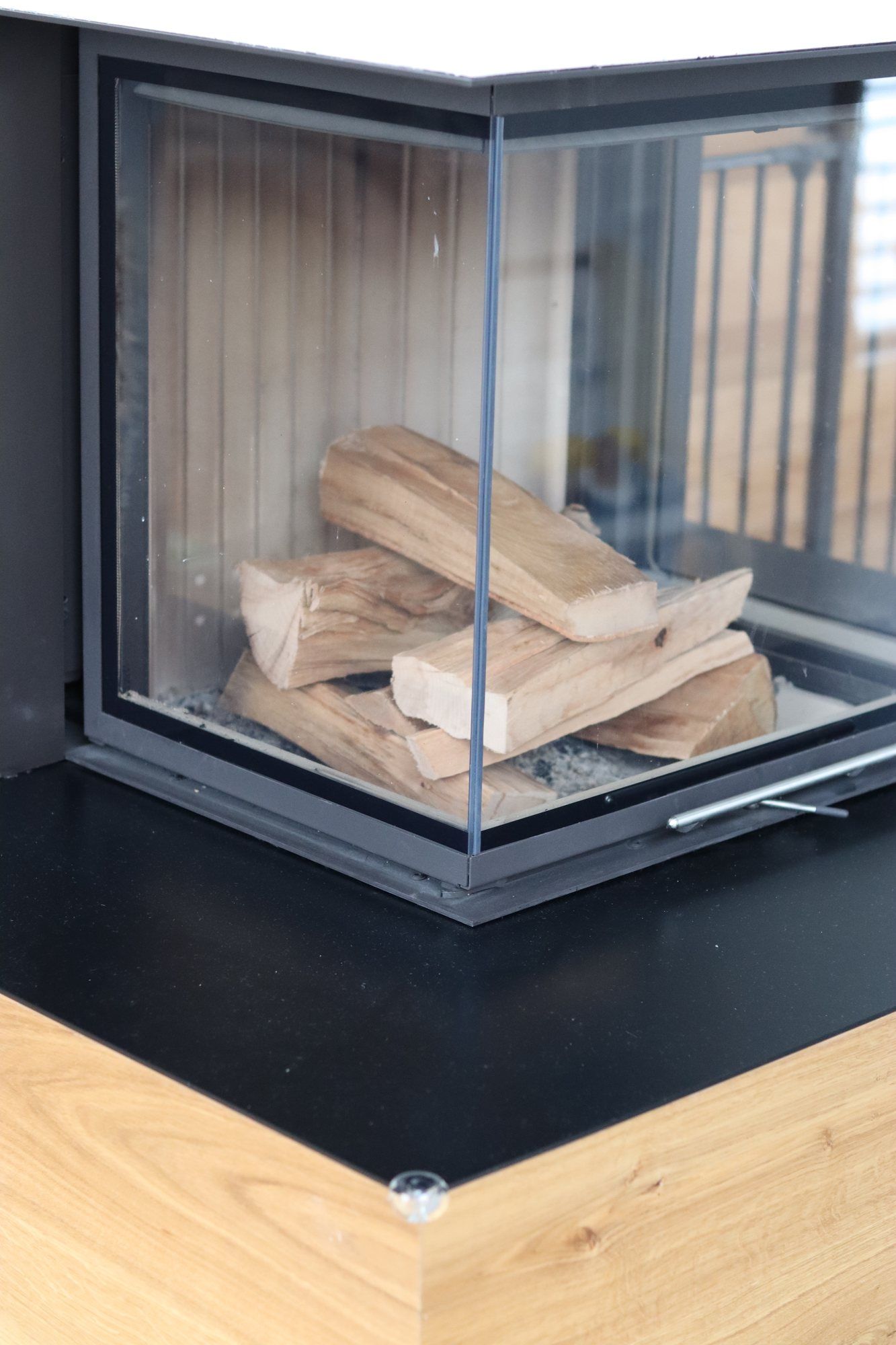 Blick in den dreiseitig verglasten Brennraum mit aufgeschichteten Holzscheiten